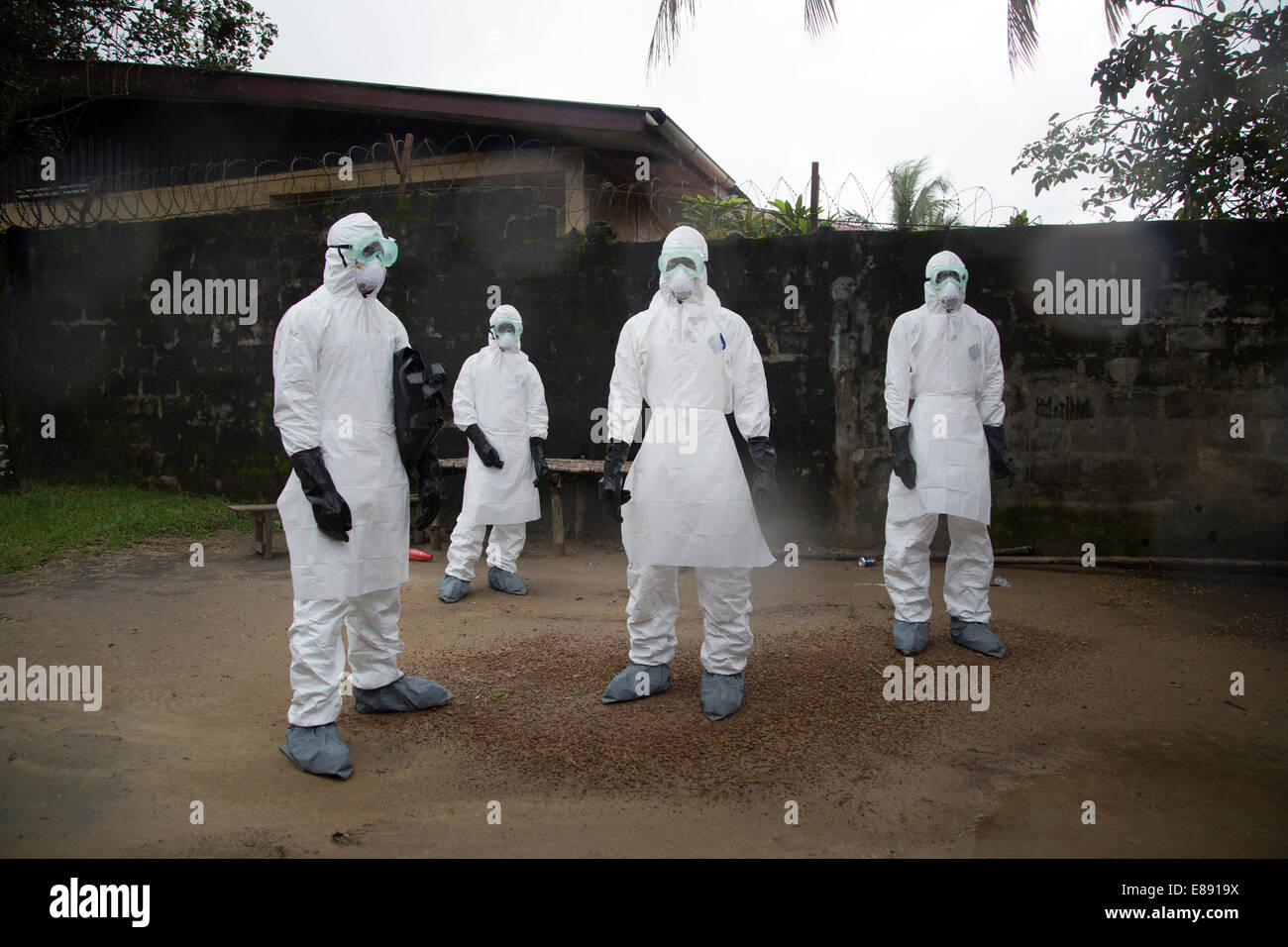 Rimozione del corpo team attende per la casa per essere spruzzato con cloro prima del loro invio per rimuovere il corpo ucciso da Ebola. Unificat Foto Stock