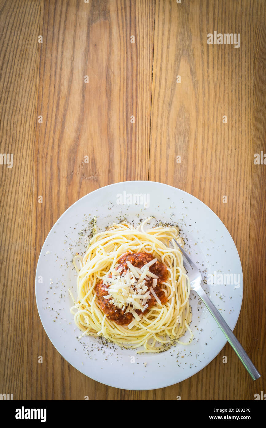 Piatto di spaghetti con la carne di suolo il ragù alla bolognese e parmigiano grattugiato su tavola in legno rustico. Foto Stock