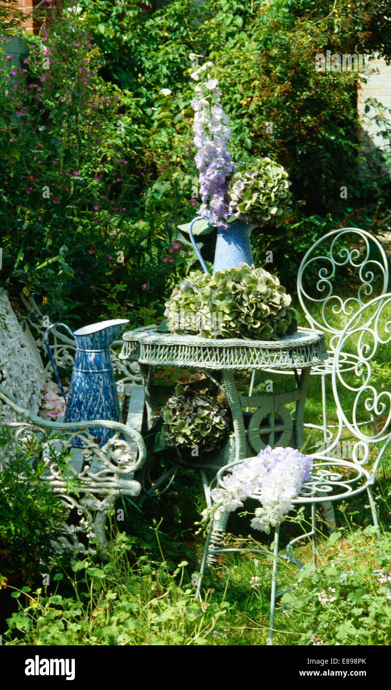 Teste di ortensie dipinto su tavola con sedie in ferro battuto in country garden Foto Stock