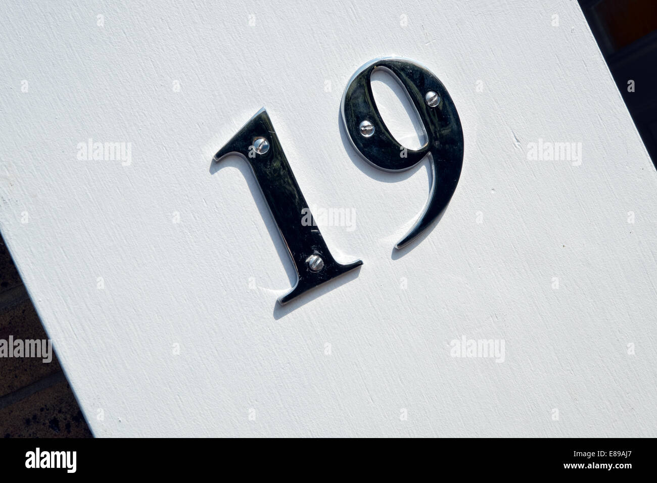 Numero di cromo 19 su uno stucco bianco parete, utilizzata per identificare la casa di indirizzo Foto Stock