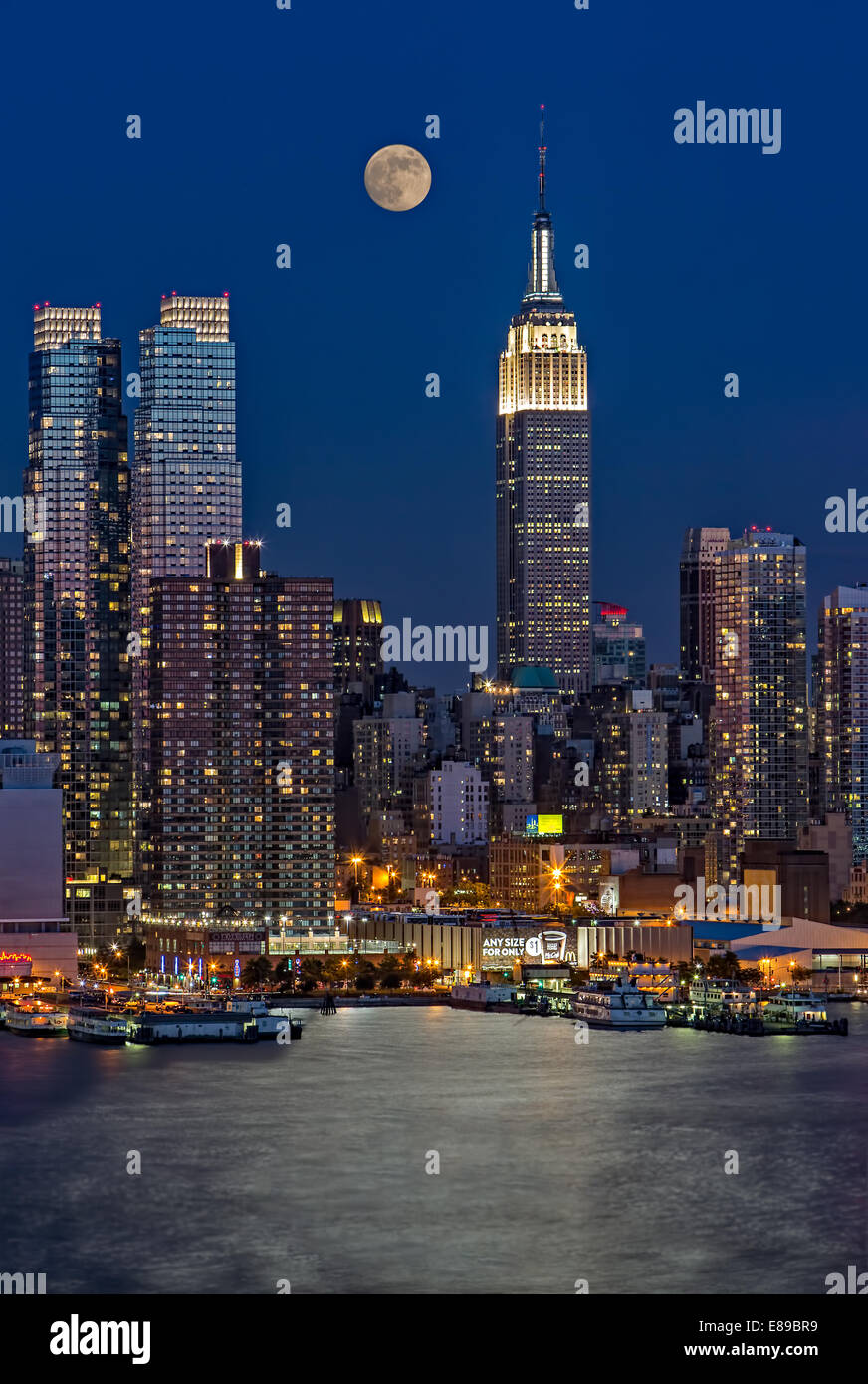 La Full Moon Rising a fianco l'Empire State Building di New York al crepuscolo. Foto Stock