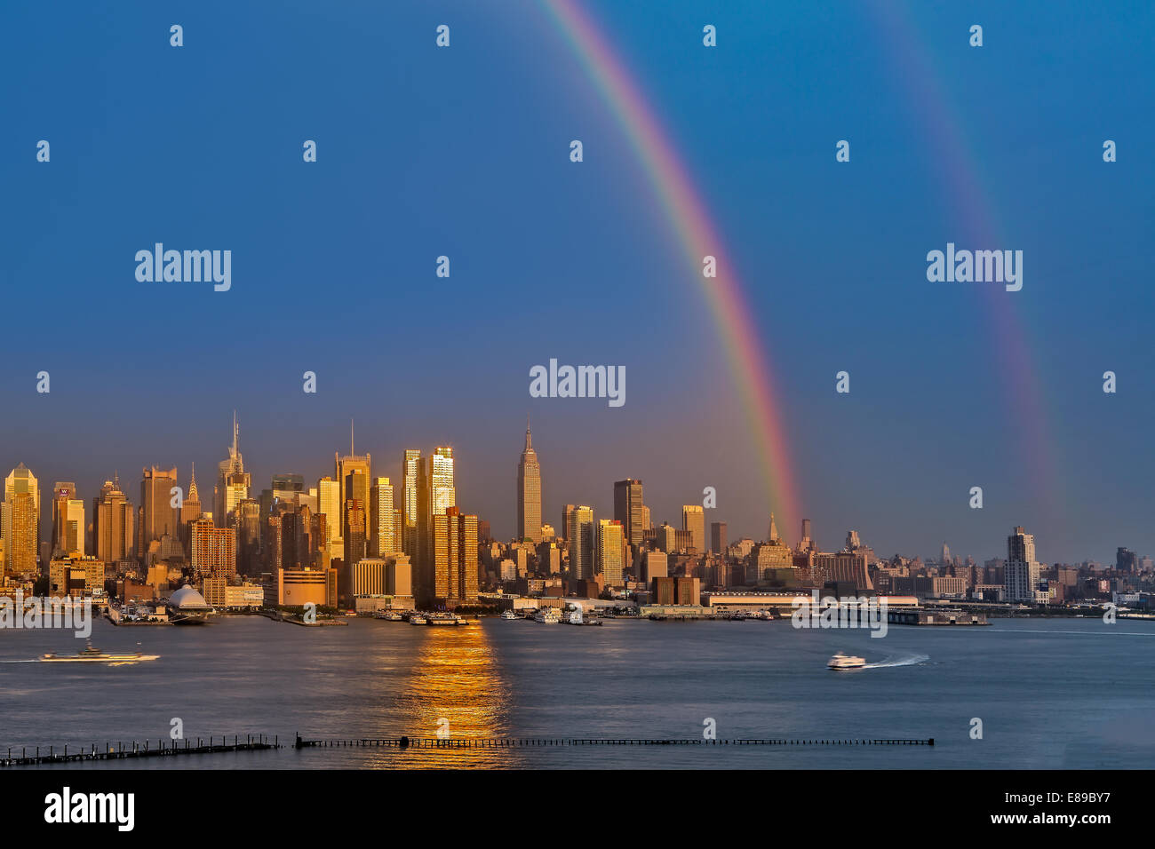 Double Rainbows emergere dopo una pioggia di estate doccia sopra la città di New York skyline al tramonto. Foto Stock