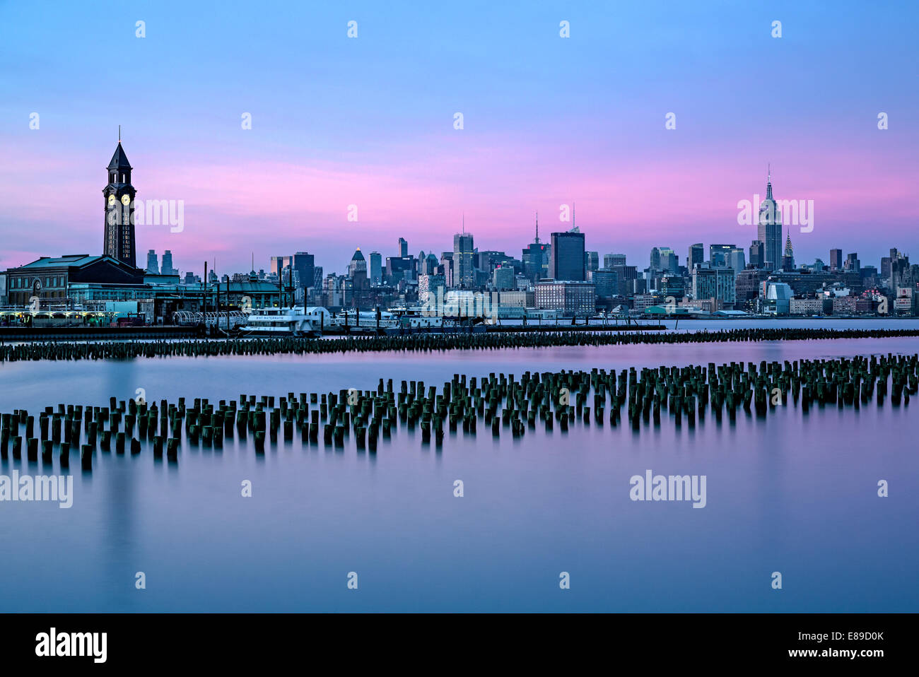 Sullo skyline di New York insieme a Empire State Building illuminato e la Erie Lackawanna terminale in Hoboken, New Jersey. Foto Stock