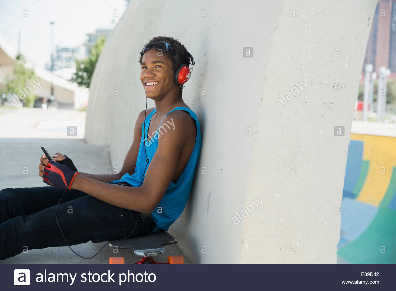 Adolescente con un telefono cellulare e le cuffie su skateboard Foto Stock