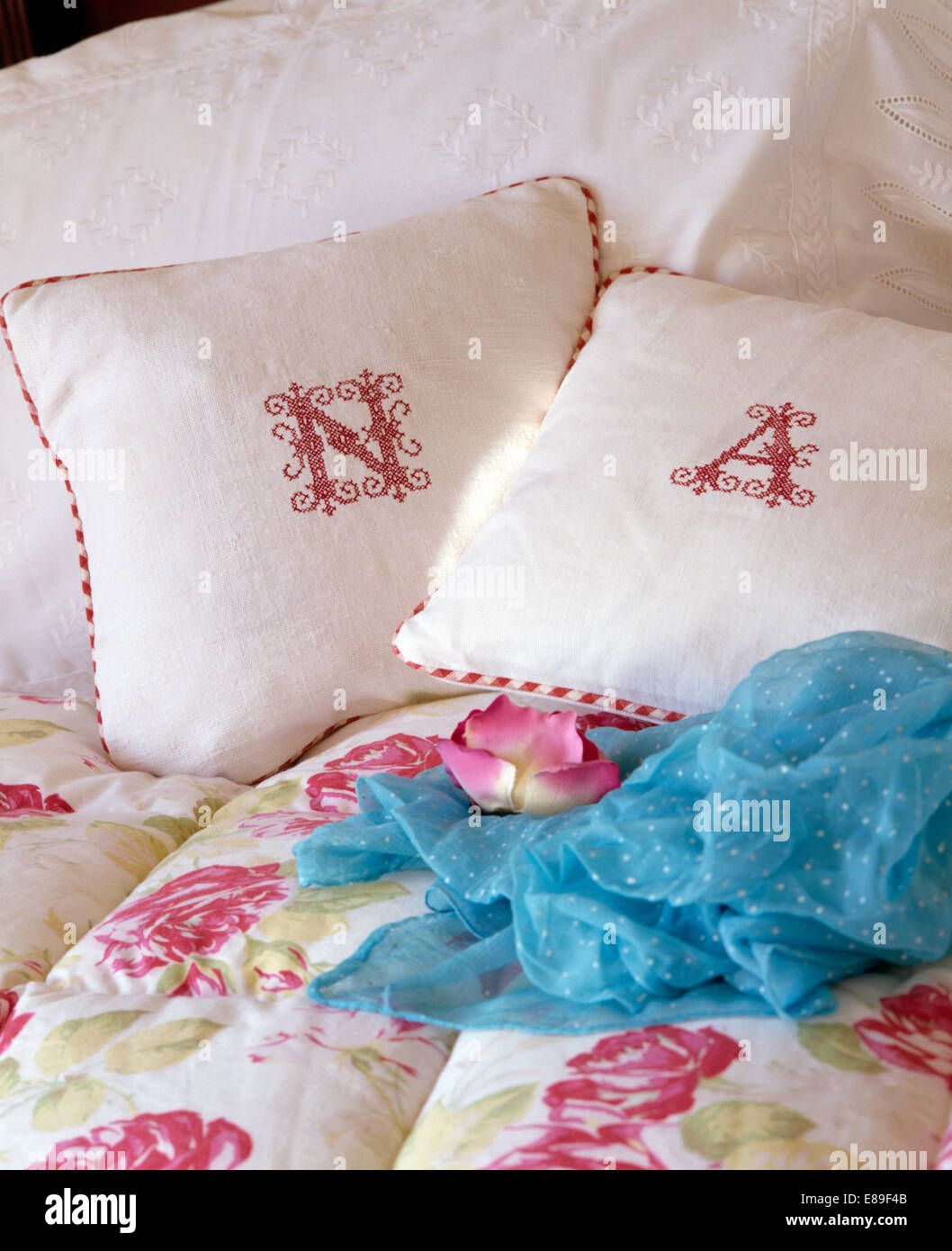 Monogrammed biancheria bianca cuscini sul letto con sciarpa turchese e rose quilt modellato Foto Stock