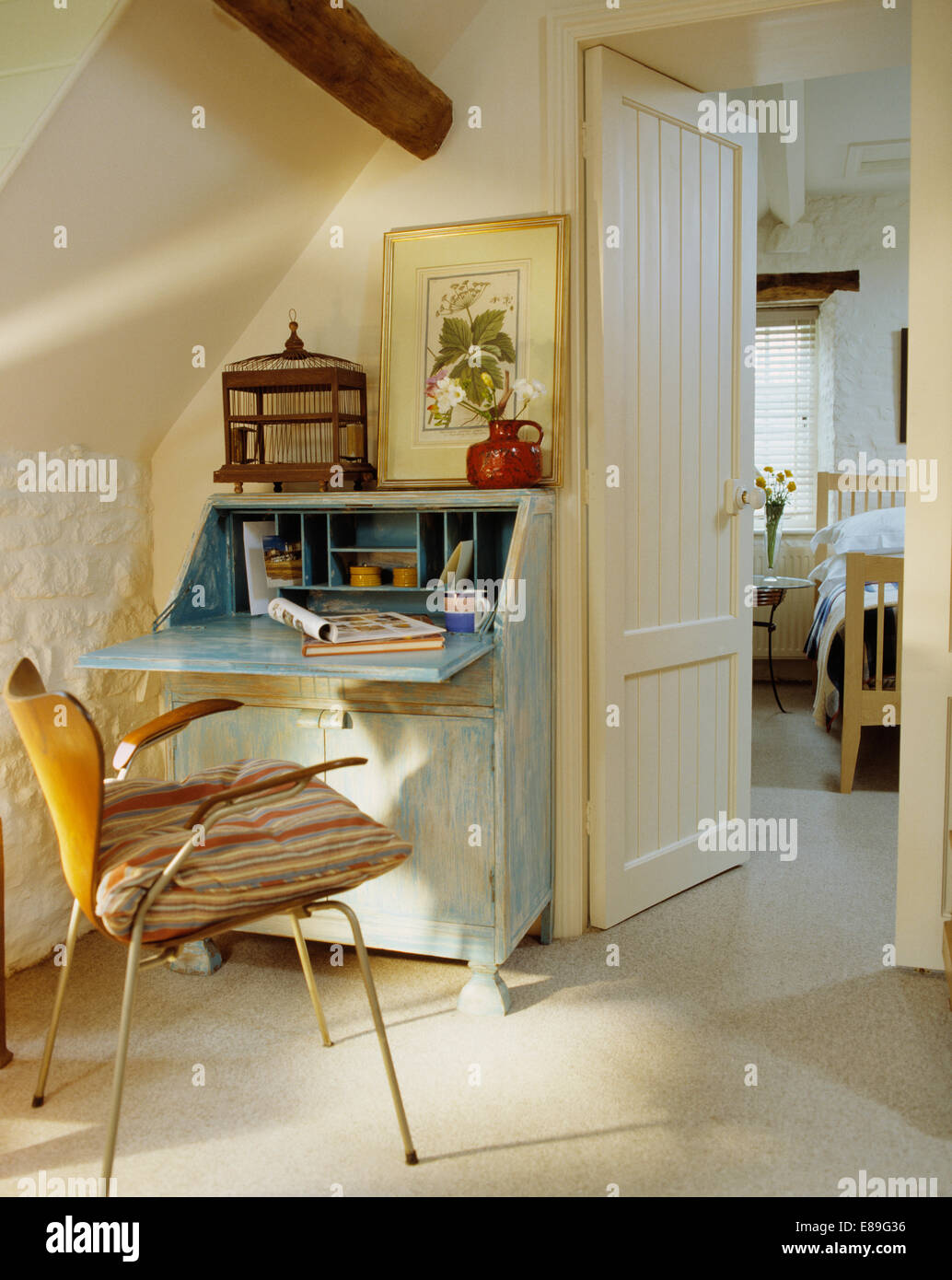 Negli anni cinquanta la sedia accanto a pale dipinte di blu scrivania in piccolo attico con lo studio di porta aperta sulla camera da letto Foto Stock