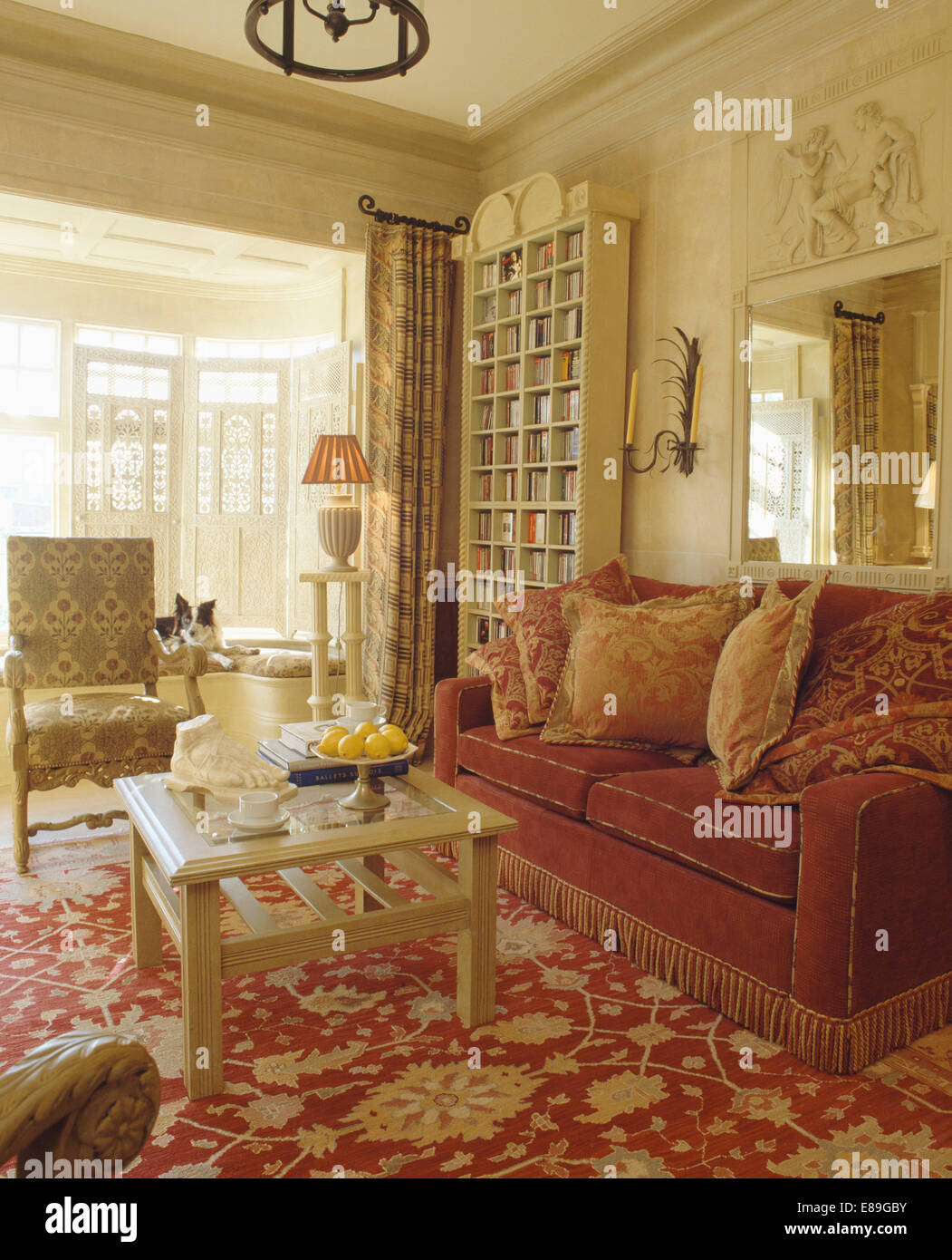 Cuscini modellato sul rosso scuro divano con frange la bordatura in crema  soggiorno con rosso e crema moquette a motivi geometrici Foto stock - Alamy