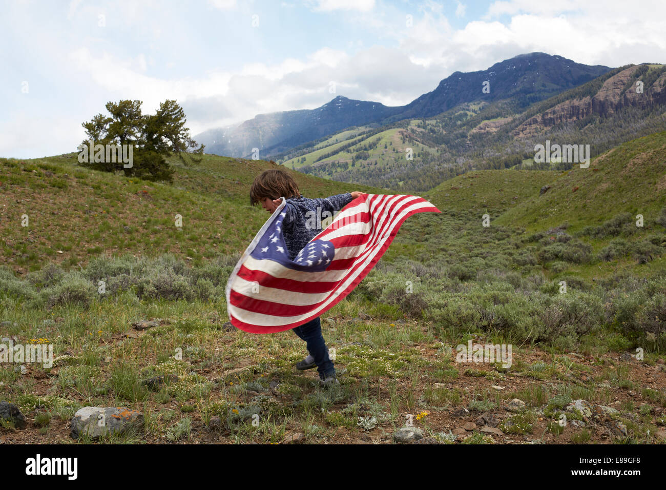 Ragazzo holding bandiera americana in colline Foto Stock
