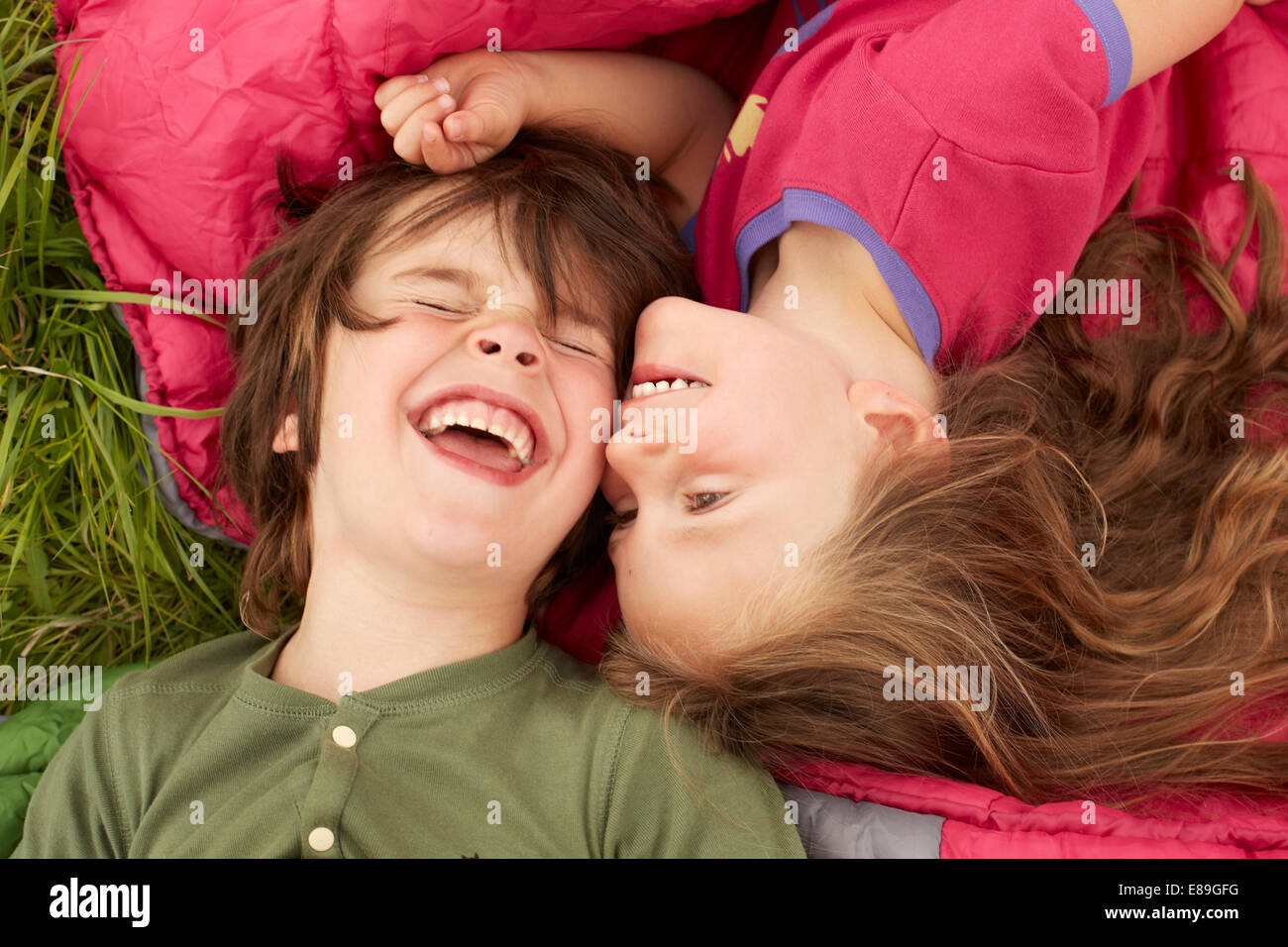 Un ragazzo e una ragazza ridere mentre posa su sacchi a pelo Foto Stock