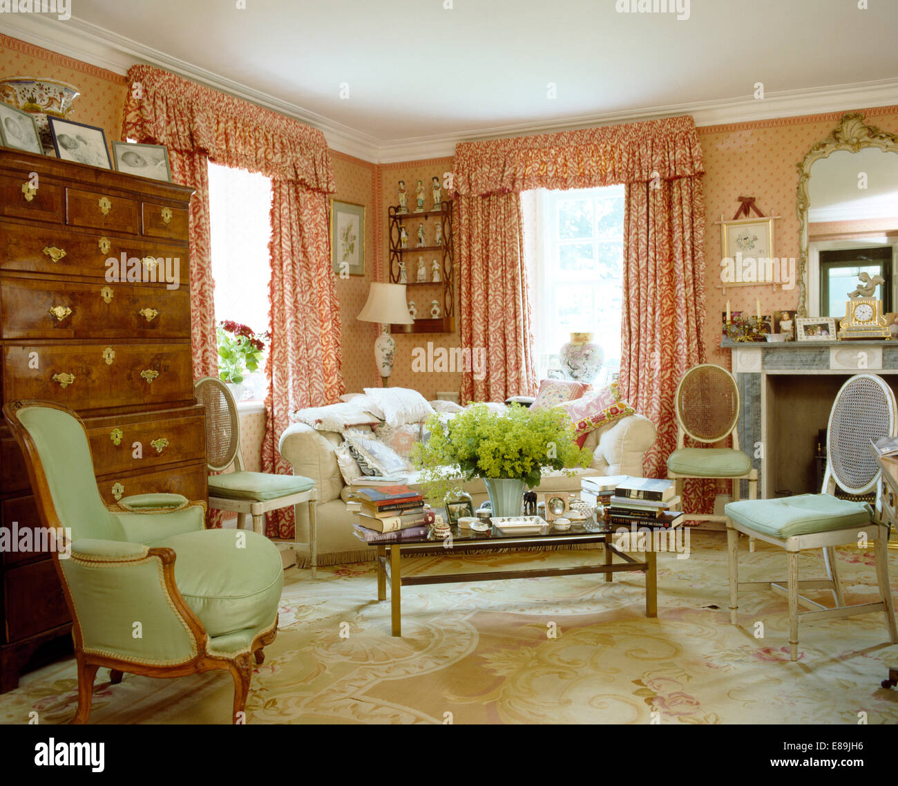 Rosso + tende bianche in rosa country living room con palloncino di antiquariato indietro sedie e confortevole poltrona e divano Foto Stock