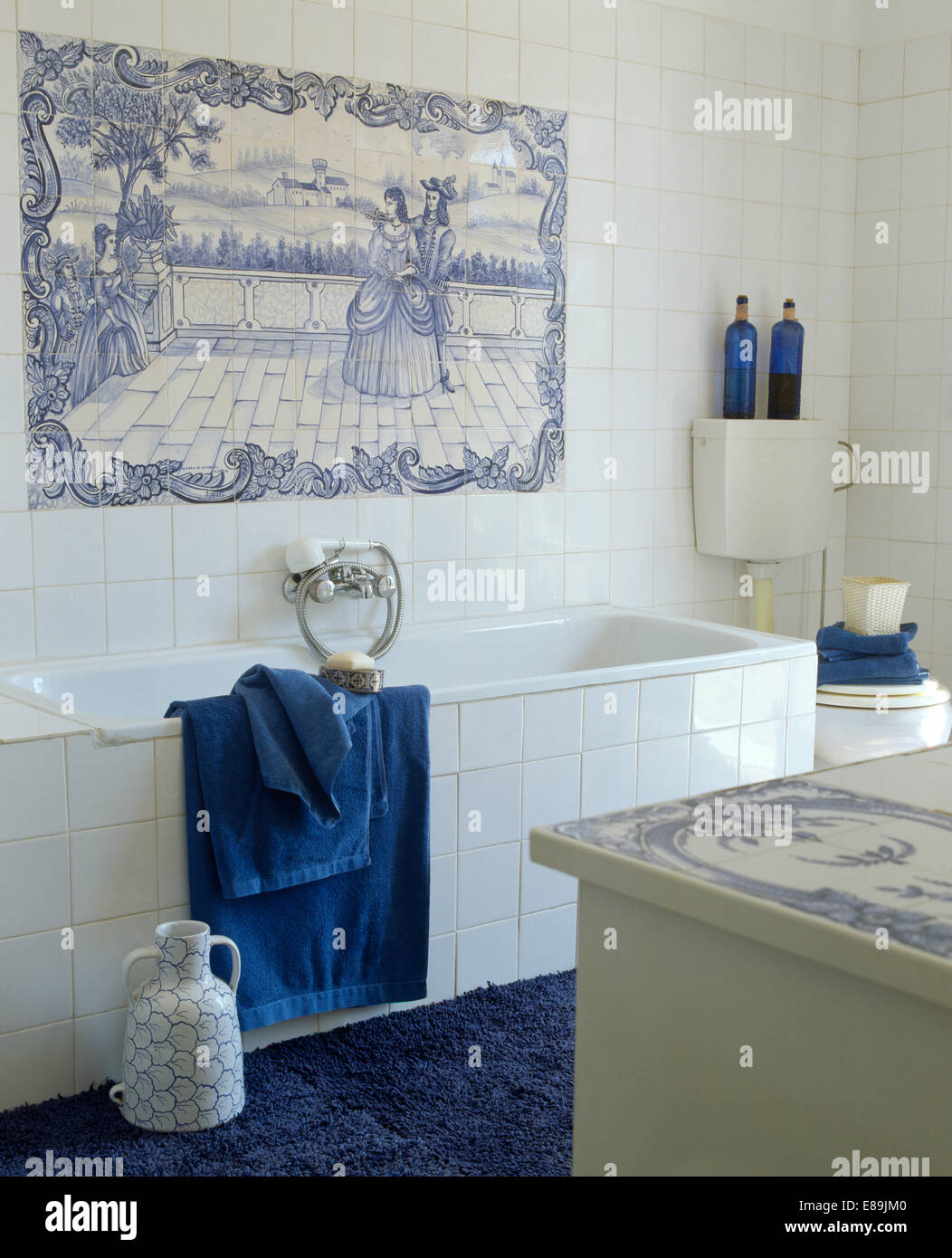 Bagno costiere con blue+bianco piastrellate murale sulla parete sopra il bagno con asciugamani blu e bianco pannello di piastrelle Foto Stock