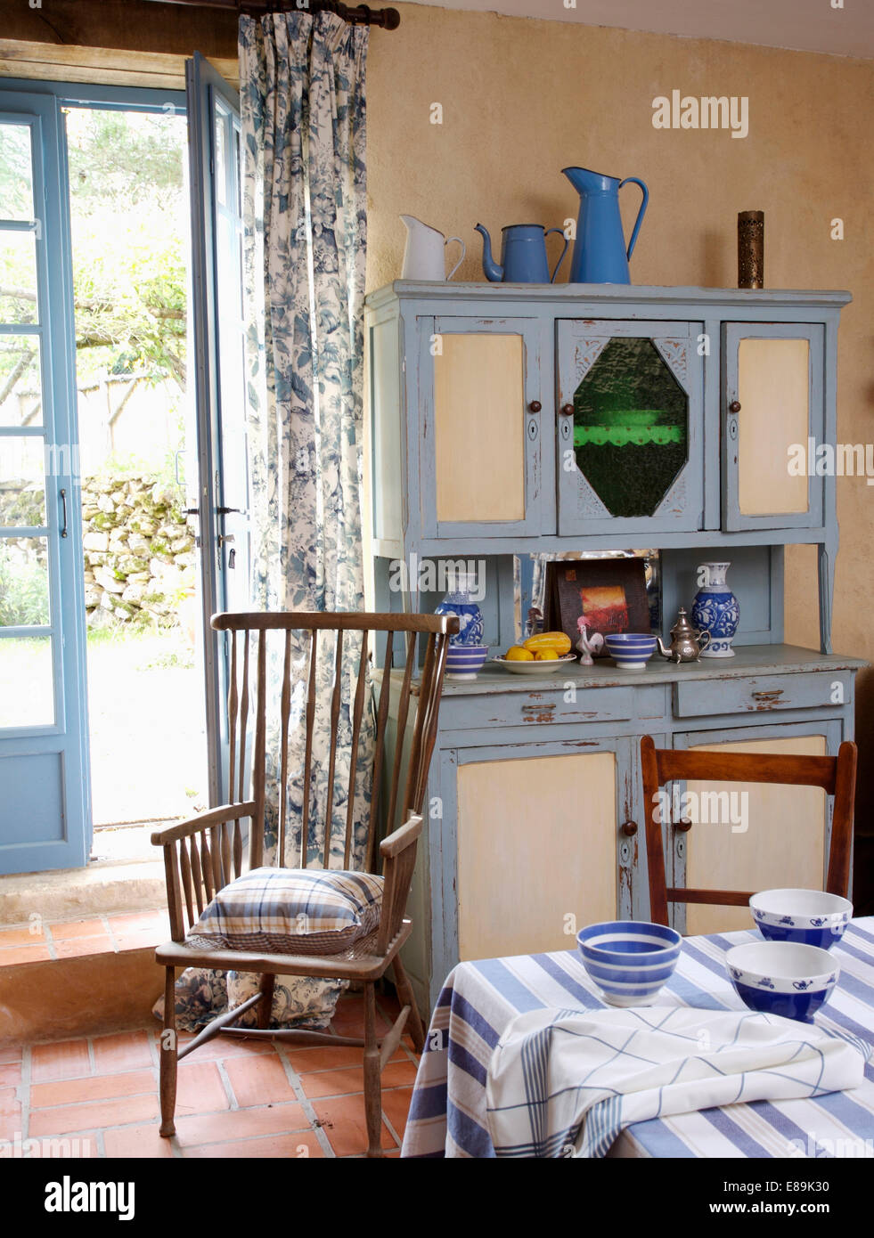 Blu e bianco degli anni cinquanta dresser nel paese cucina sala da pranzo Camera con sedia in legno nella parte anteriore delle porte Francesi Foto Stock