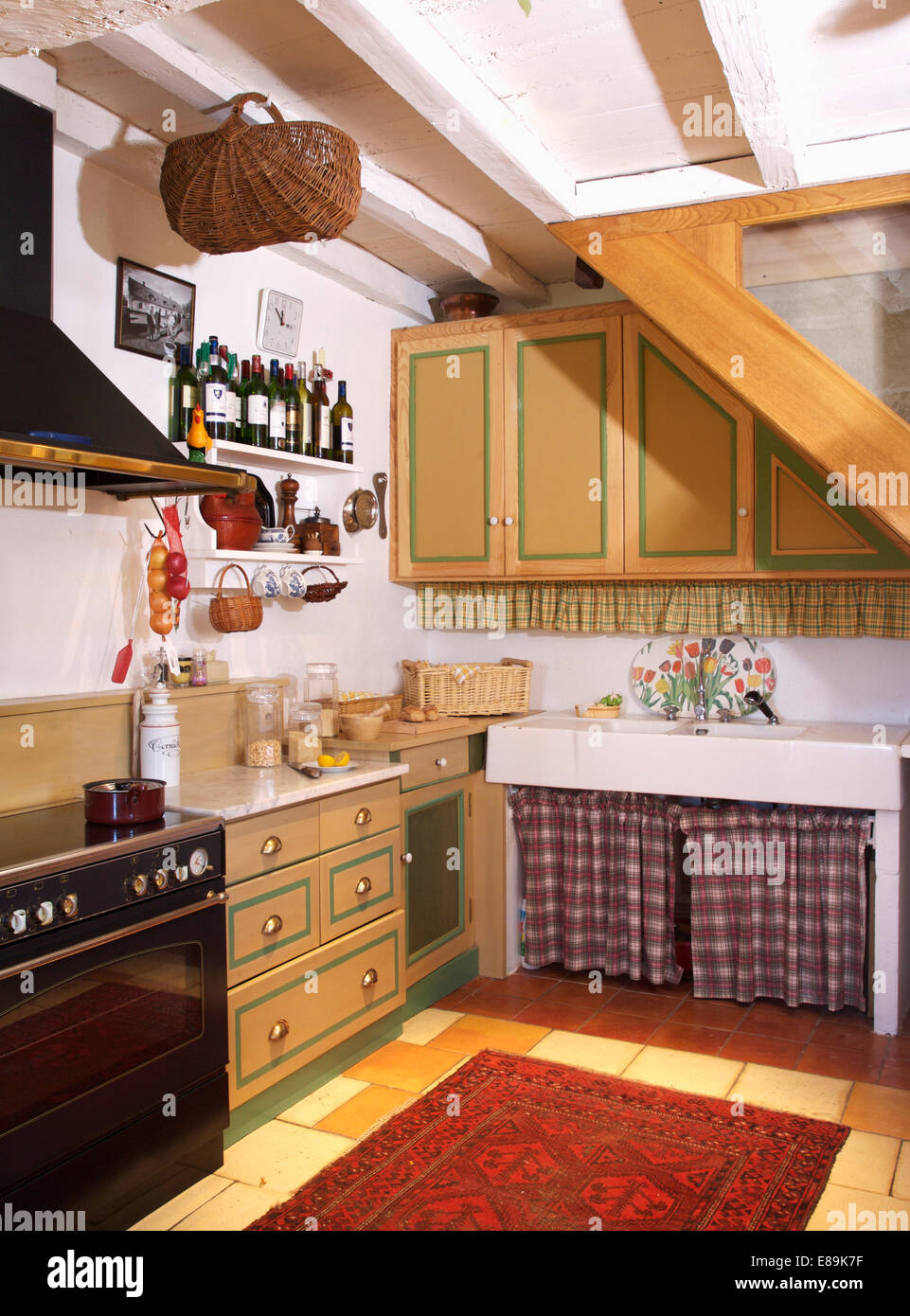 Marrone e bianco controllato tende sotto lavello in cucina di paese con dipinti dotati di unità Foto Stock