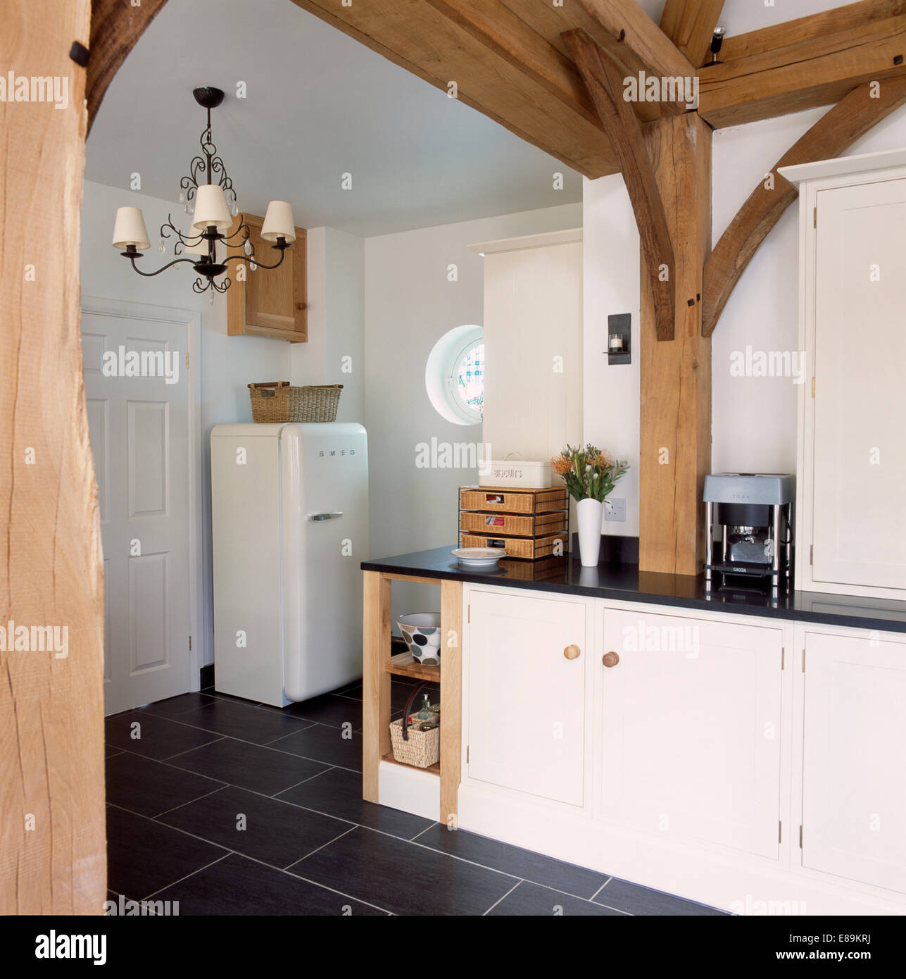 Grandi travi in legno nella conversione del granaio cucina con frigo Smeg e pavimento di ardesia Foto Stock