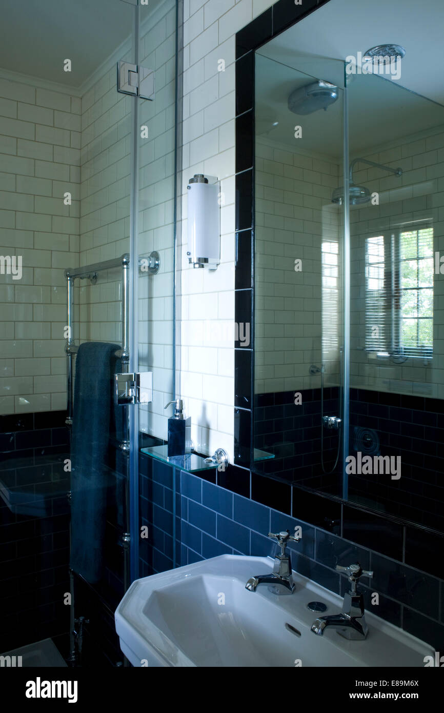 Specchio sopra lavandino in una moderna stanza da bagno con piastrelle blu Foto Stock