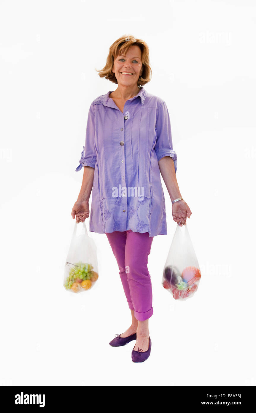 Senior donna tenendo la frutta e la verdura in una busta di plastica, sorridente, ritratto Foto Stock