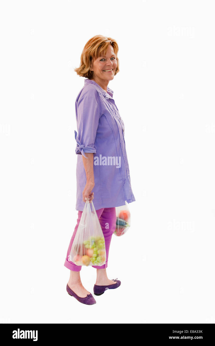 Senior donna tenendo la frutta e la verdura in una busta di plastica, sorridente, ritratto Foto Stock