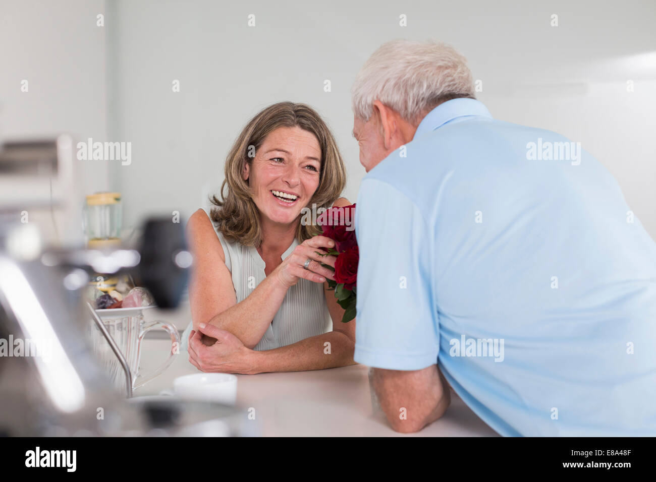 Senior uomo dando rose rosse per donna Foto Stock