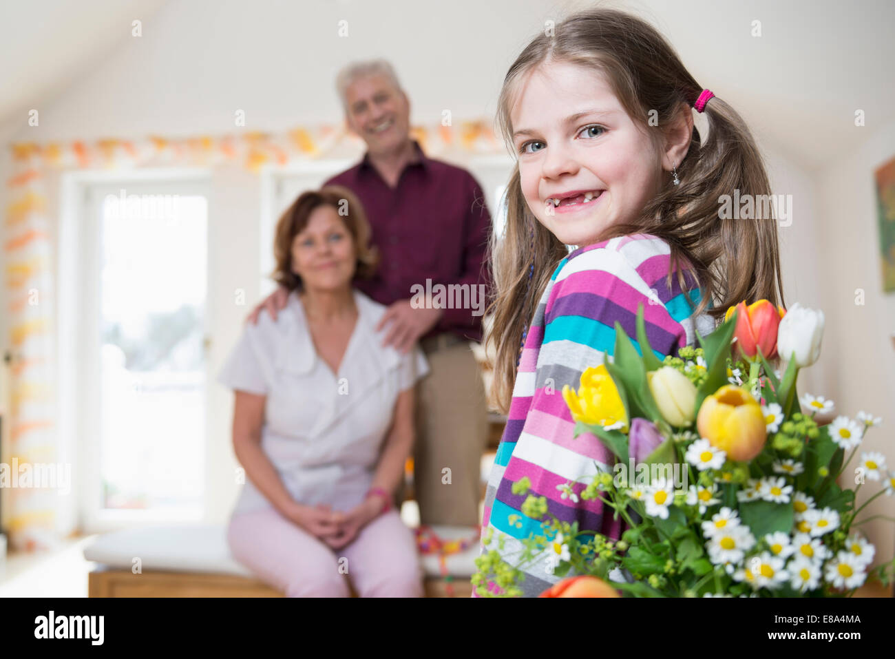 La nipote bouquet di handover alla nonna e nonno in background Foto Stock