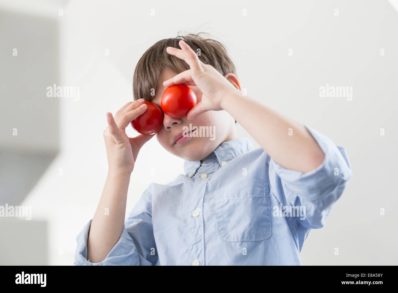 Ragazzo che si affaccia con pomodori Foto Stock
