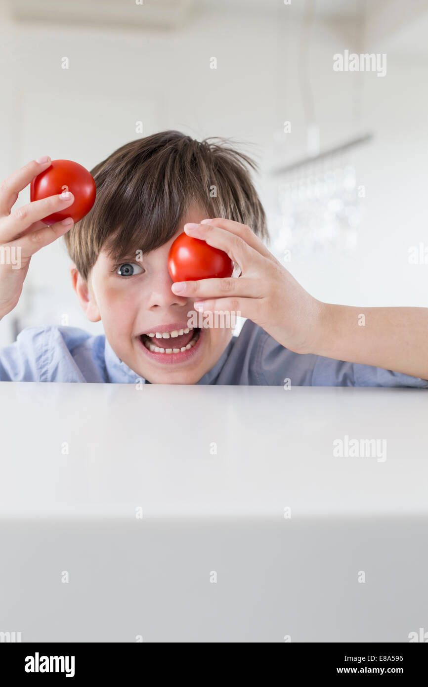 Ragazzo che si affaccia con pomodori Foto Stock