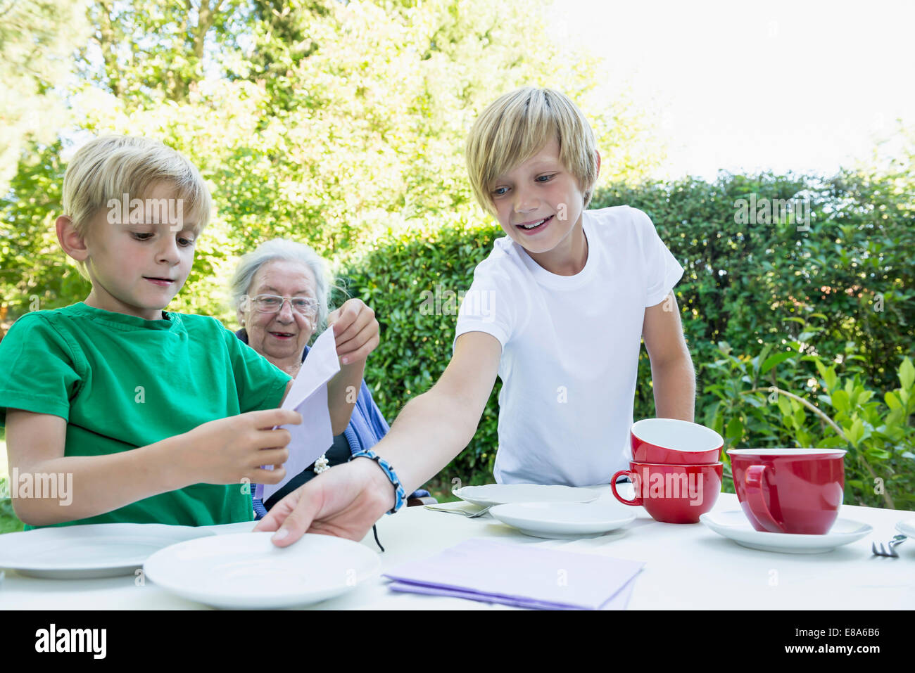 Due nipoti che stabilisce la tabella per la sua nonna Foto Stock