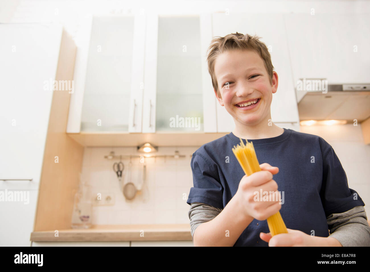 Ragazzo sorridente holding spaghetti Foto Stock