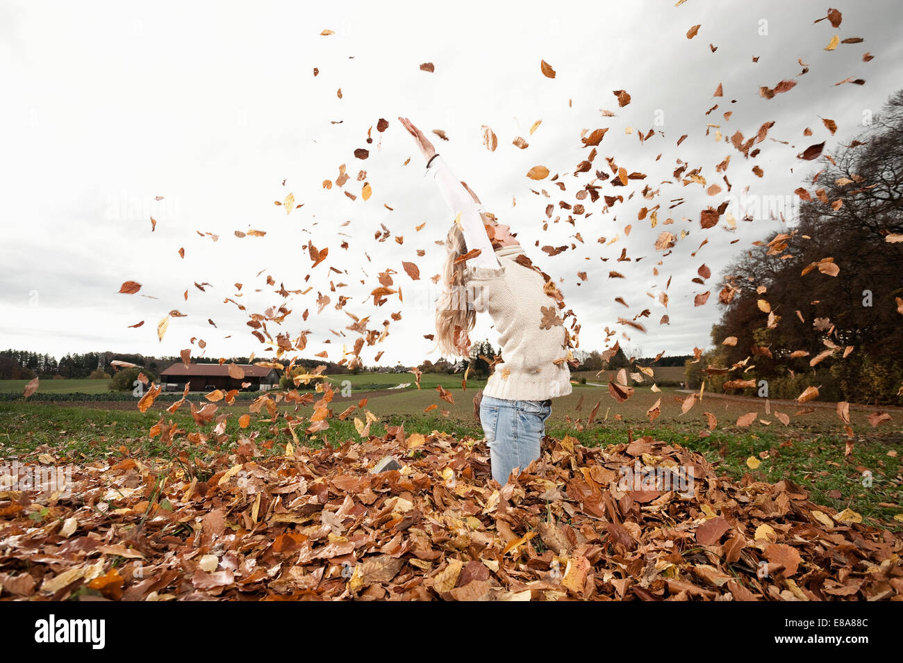 Felice ragazza gettando le foglie di autunno Foto Stock
