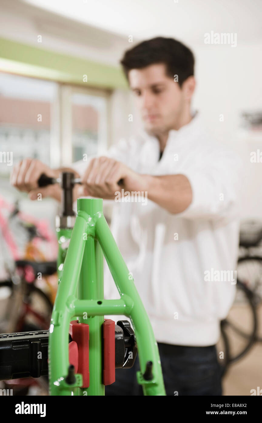 Giovane uomo che lavora sul telaio di bicicletta Foto Stock