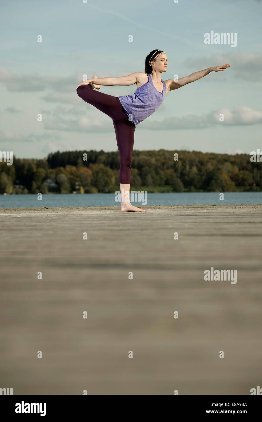 La donna a praticare yoga sul molo, Woerthsee, Baviera, Germania Foto Stock