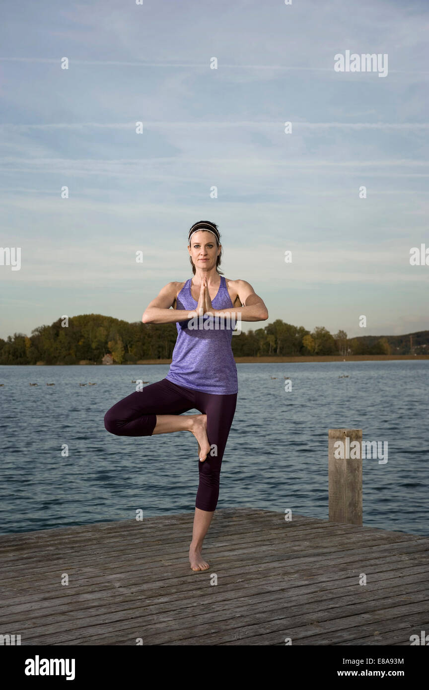 La donna a praticare yoga sul molo, Woerthsee, Baviera, Germania Foto Stock