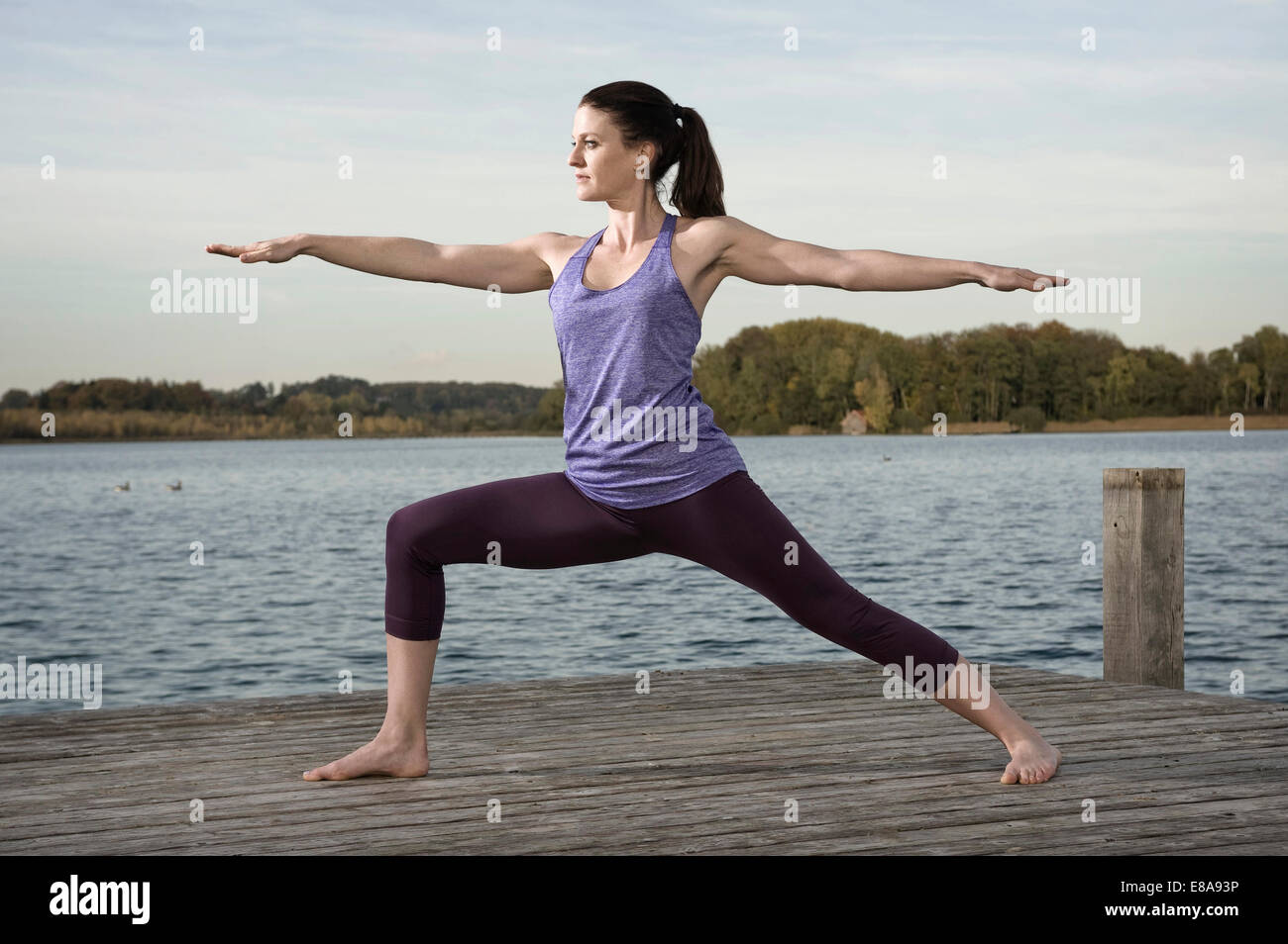 La donna a praticare yoga sul molo, Woerthsee, Baviera, Germania Foto Stock