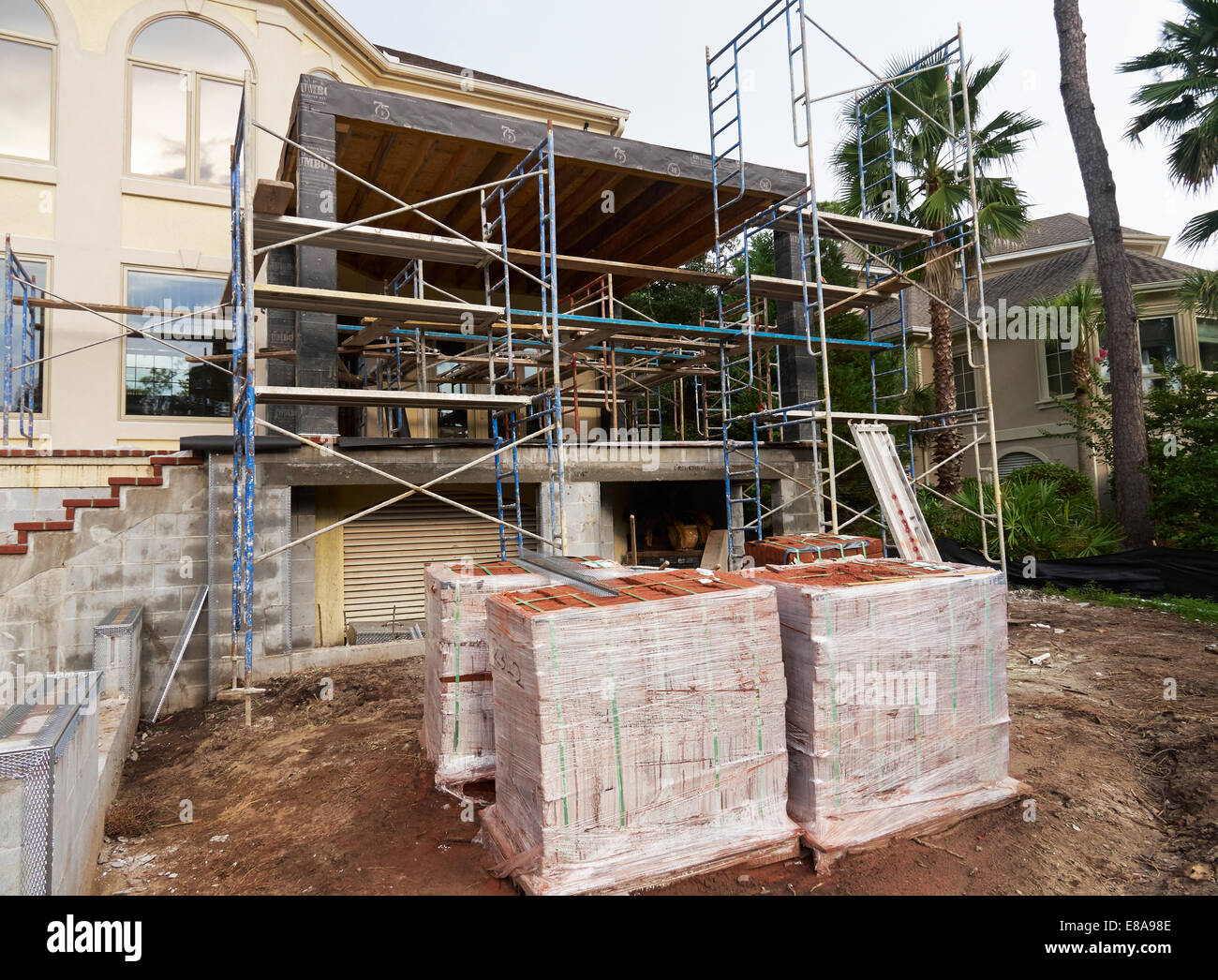 Una casa prolungamento essendo costruito con i ponteggi e una fornitura di mattoni. Foto Stock