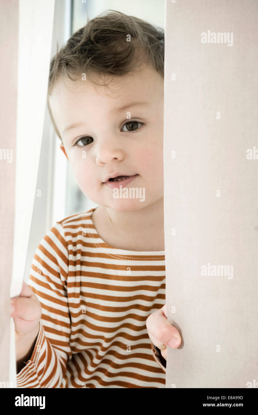 Ritratto di ragazzo giocando con tendina Foto Stock
