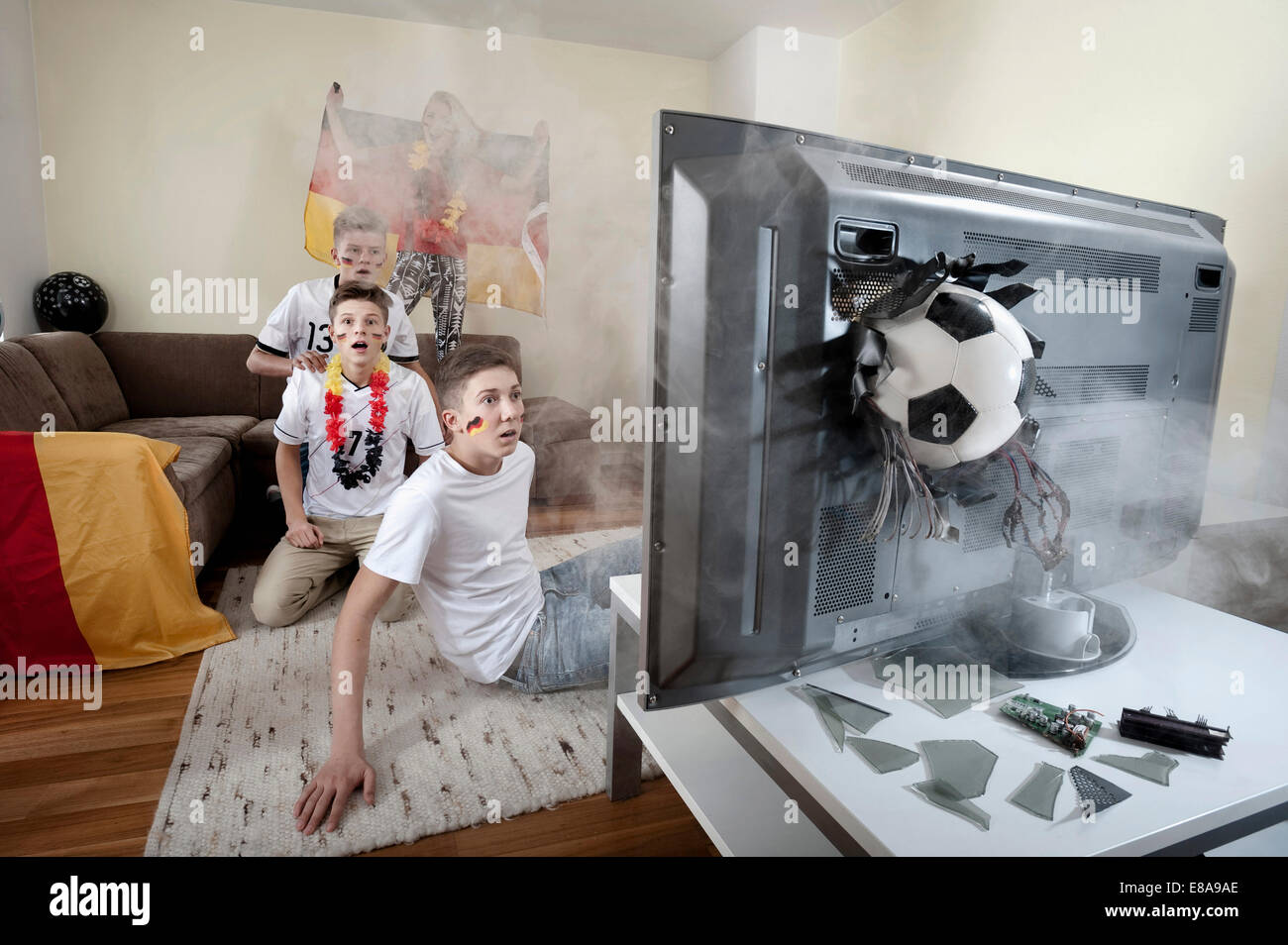 Teenage soccer fans in salotto con sfera demolendo la TV Foto Stock