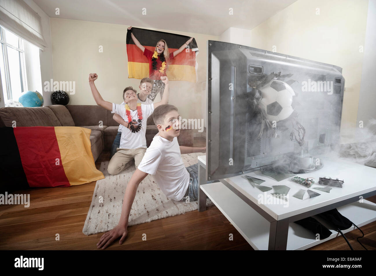 Teenage soccer fans in salotto con sfera demolendo la TV Foto Stock