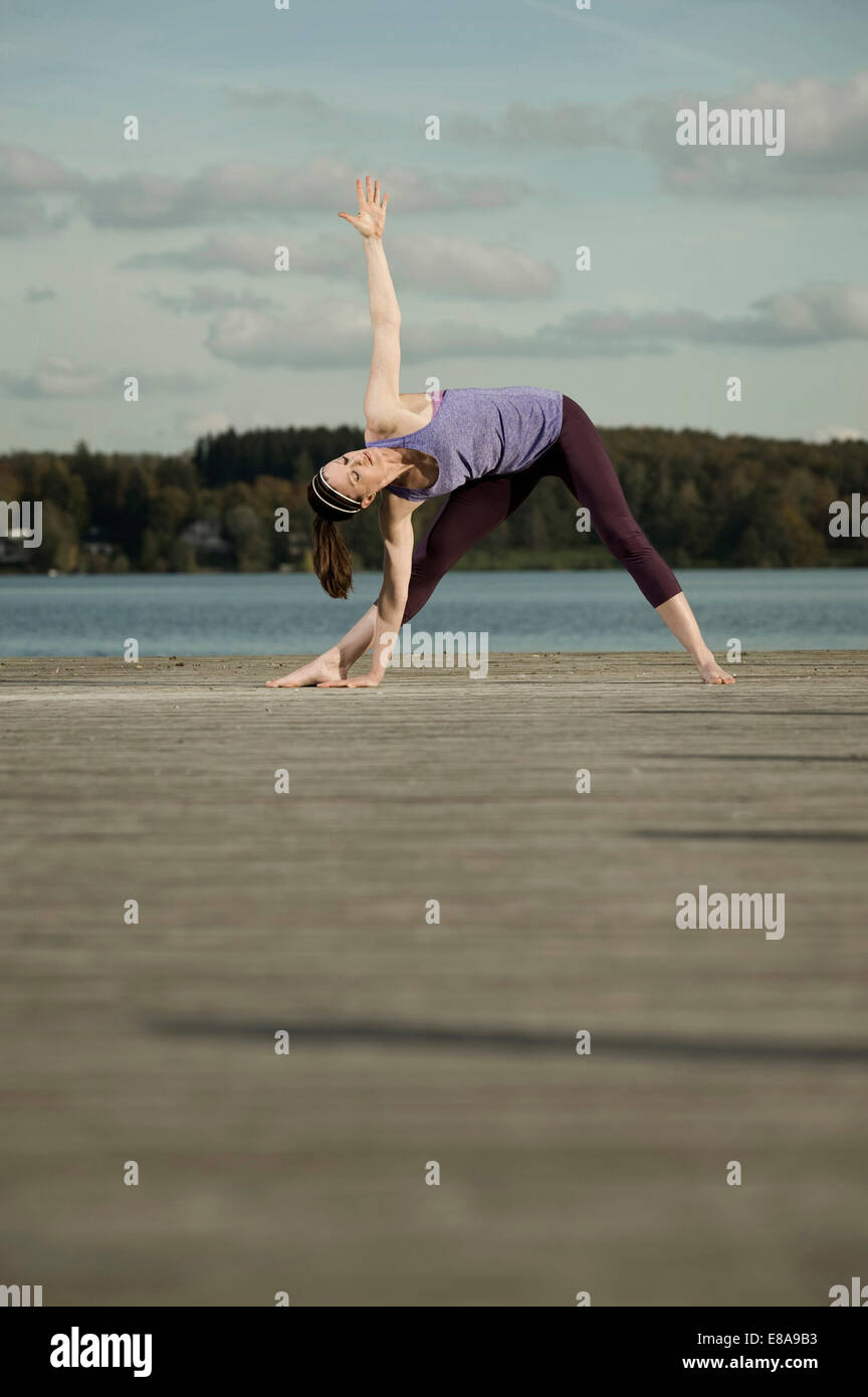 La donna a praticare yoga sul molo, Woerthsee, Baviera, Germania Foto Stock