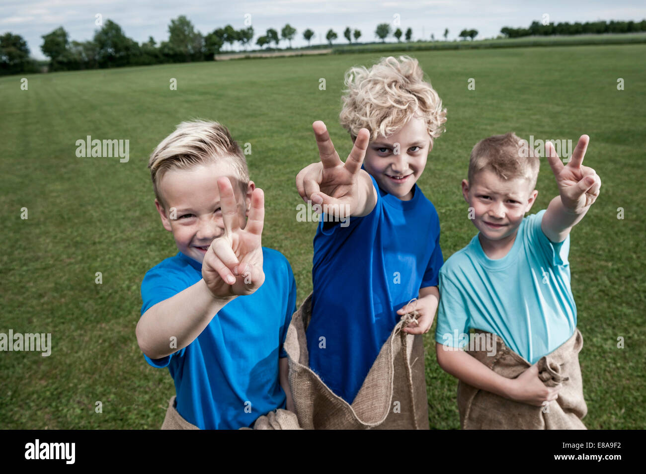 Tre giovani ragazzi bionda ponendo segno di vittoria Foto Stock
