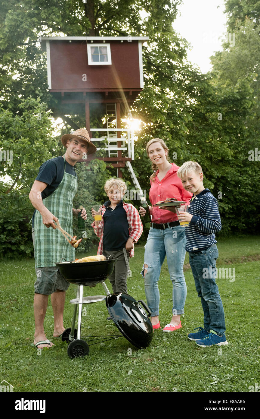 Giovane famiglia giardino barbecue kids tree-house Foto Stock