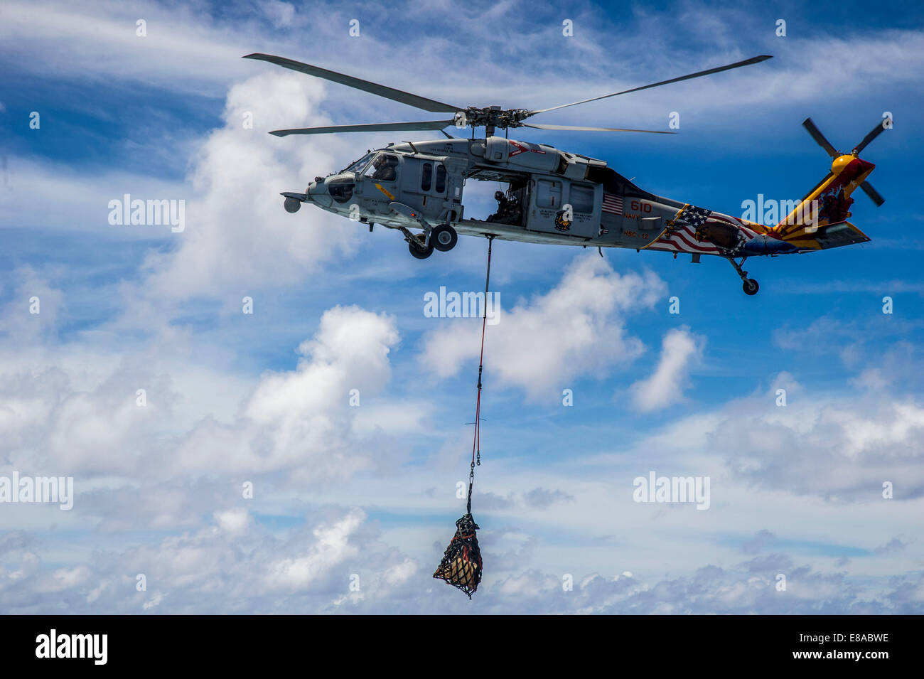 Un U.S. Navy MH-60S Seahawk elicottero attaccata al mare in elicottero Combat Squadron (HSC) 12 offre materiali di consumo per il missile destroyer USS Fitzgerald (DDG 62) durante un rifornimento in mare nell'Oceano Pacifico sett. 20, 2014. Il Fitzgerald era particol Foto Stock