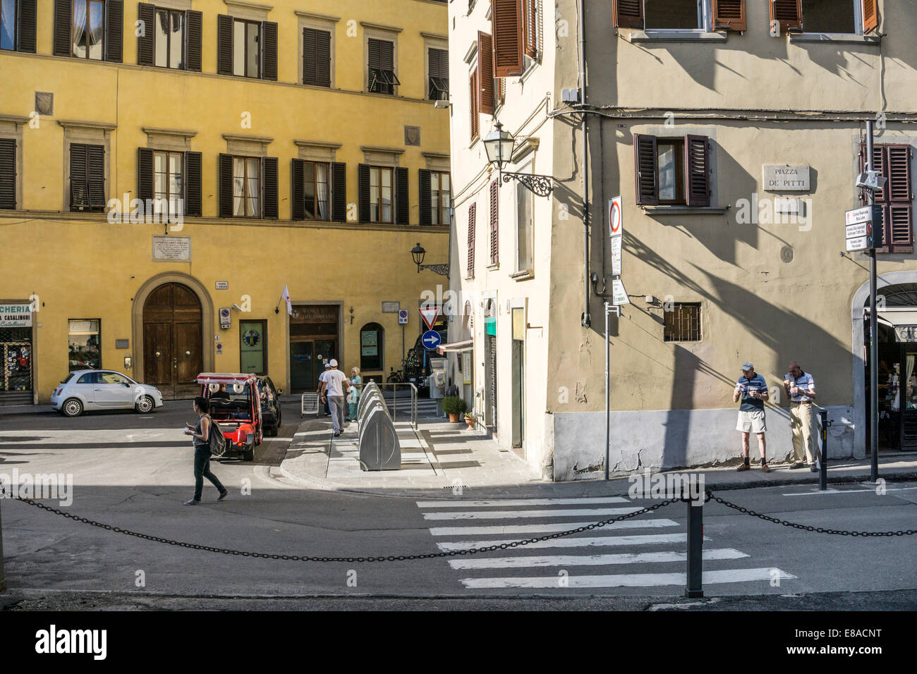 Giallo Ocra e il colore definisce lo spazio della piccola Piazza de Pitti come persone fanno il loro quotidiano di commissioni & 2 uomini anziani godono di gelato il gelato Foto Stock