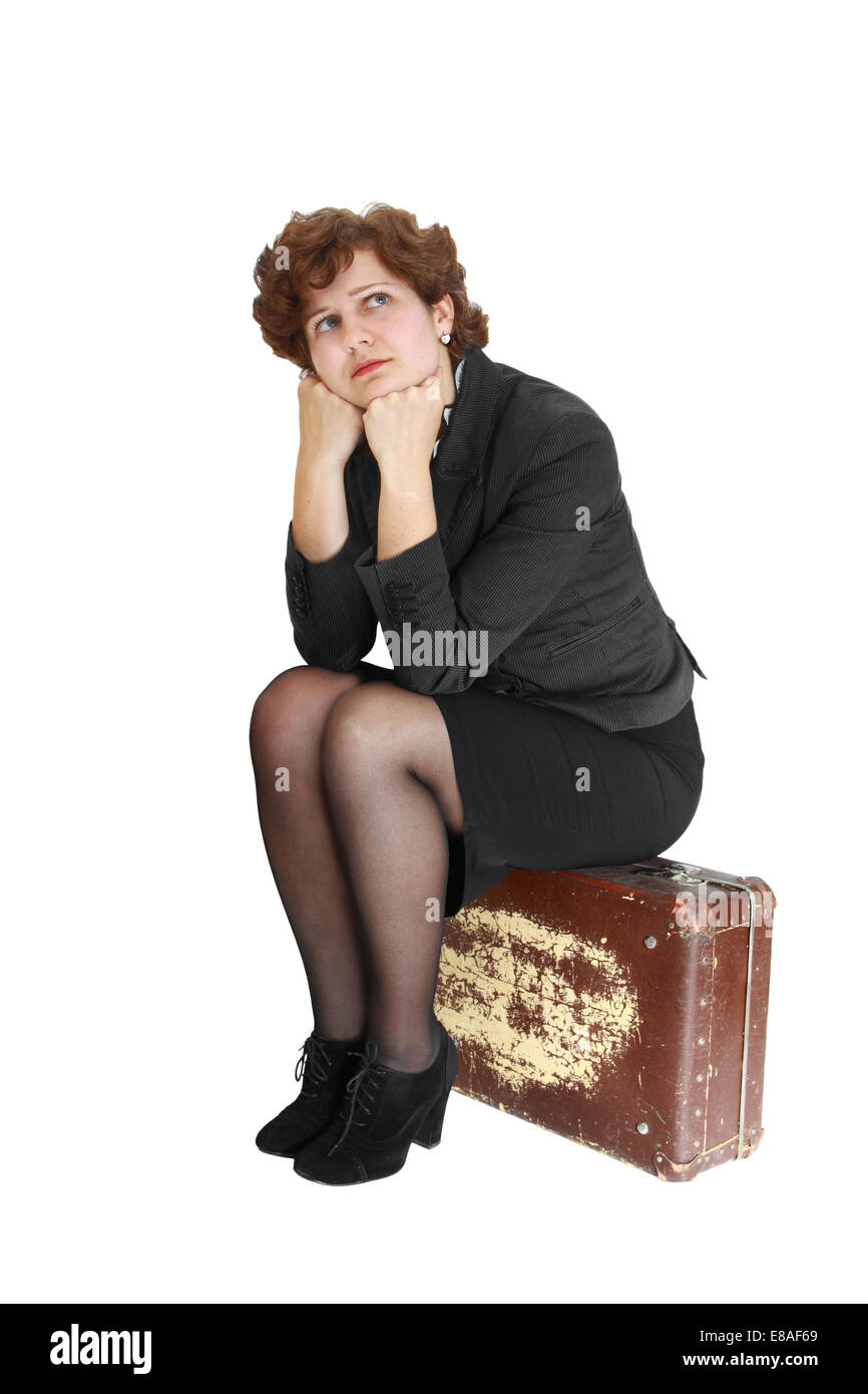 Giovane donna nel pensiero si siede su una vecchia valigia graffiato isolati su sfondo bianco Foto Stock