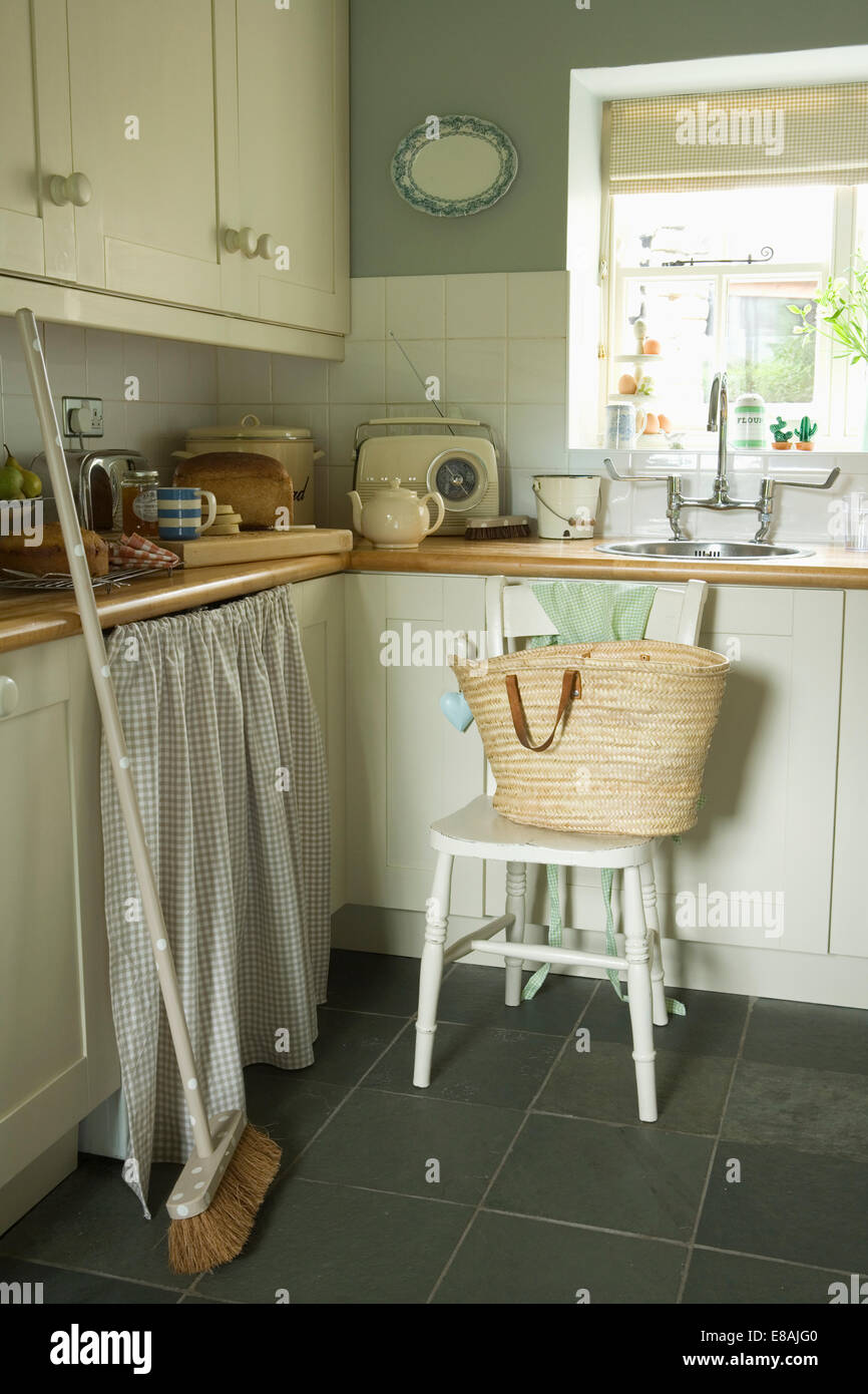 Ginestra contro le unità di cottura con controllato tende in cottage cucina con cestello su bianco sedia in legno Foto Stock