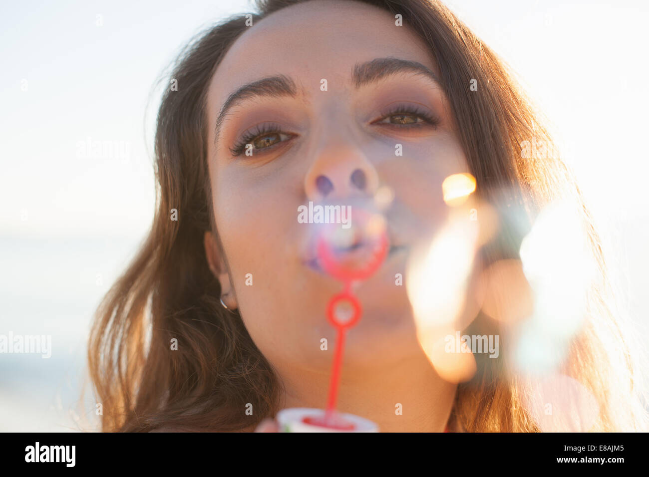 Close up della giovane donna a soffiare bolle sulla spiaggia, Castiadas, Sardegna, Italia Foto Stock