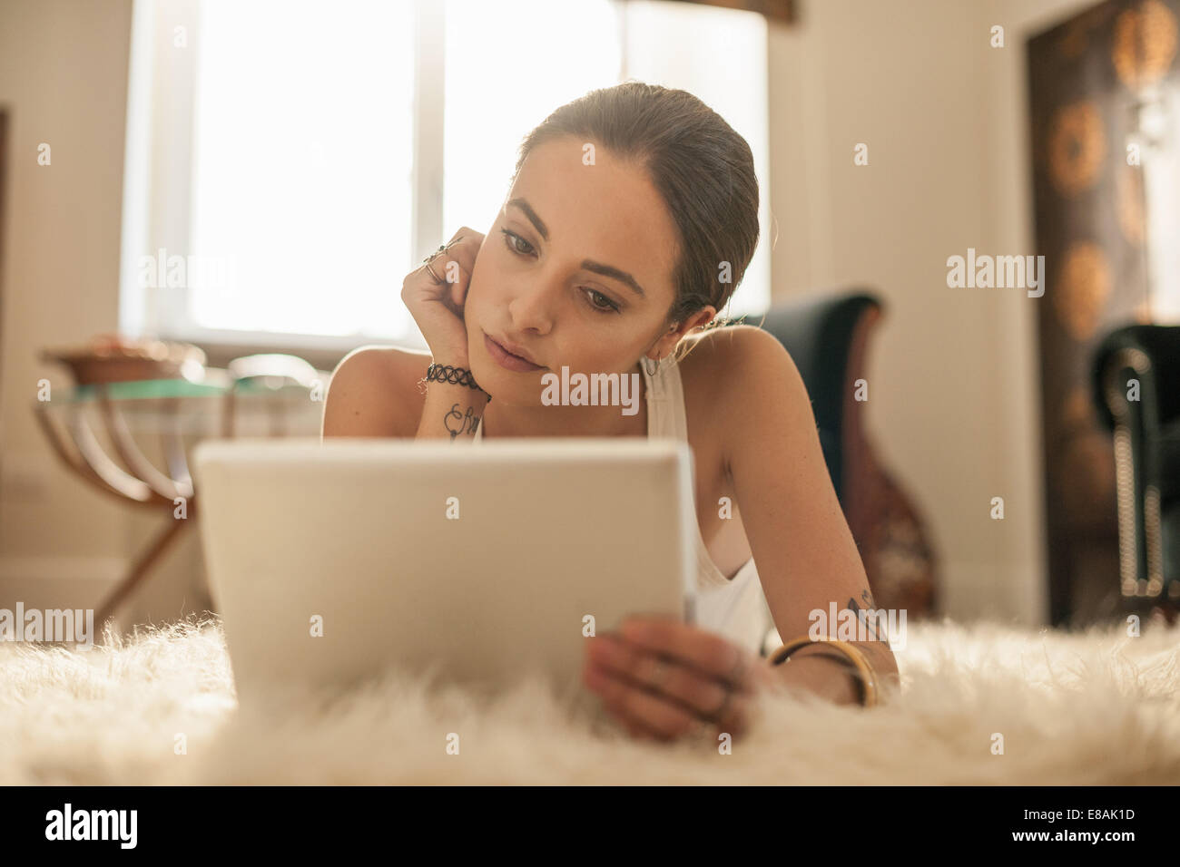 Giovane donna giacente sul salotto rug guardando a tavoletta digitale Foto Stock