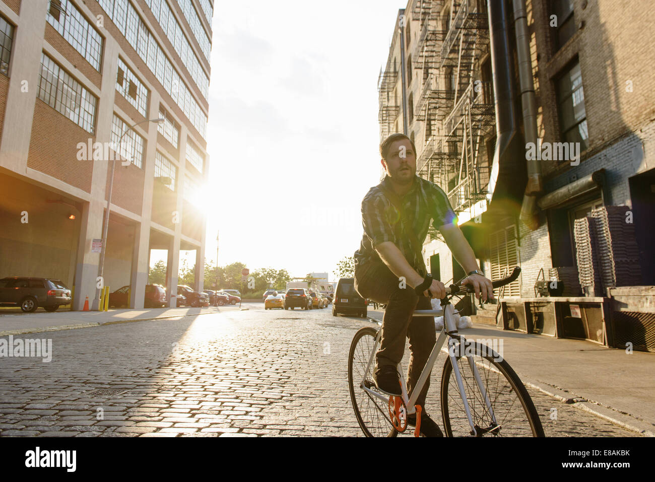 Messenger maschio in bicicletta lungo una strada di città Foto Stock