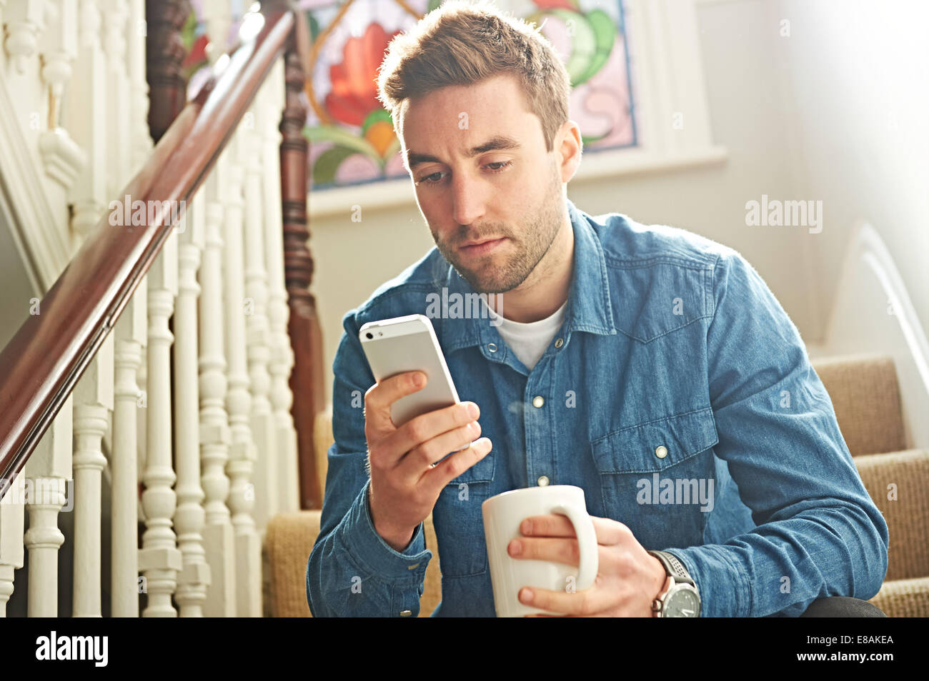 L'uomo utilizza lo smartphone su scale Foto Stock