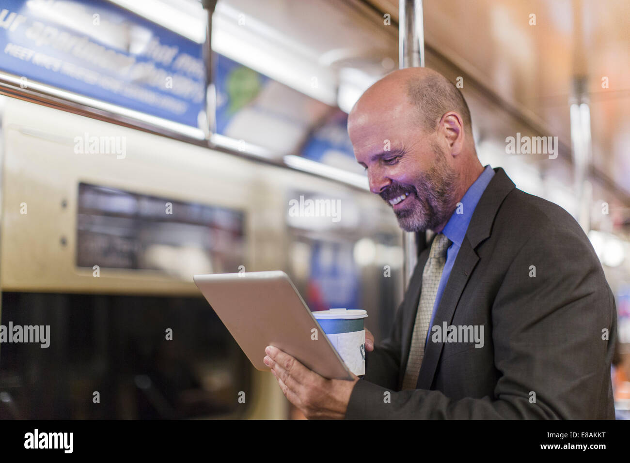 Uomo maturo sul treno della metropolitana holding tavoletta digitale Foto Stock