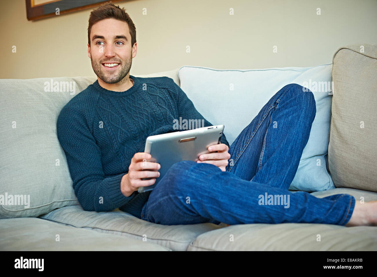Uomo con tavoletta digitale sul divano Foto Stock