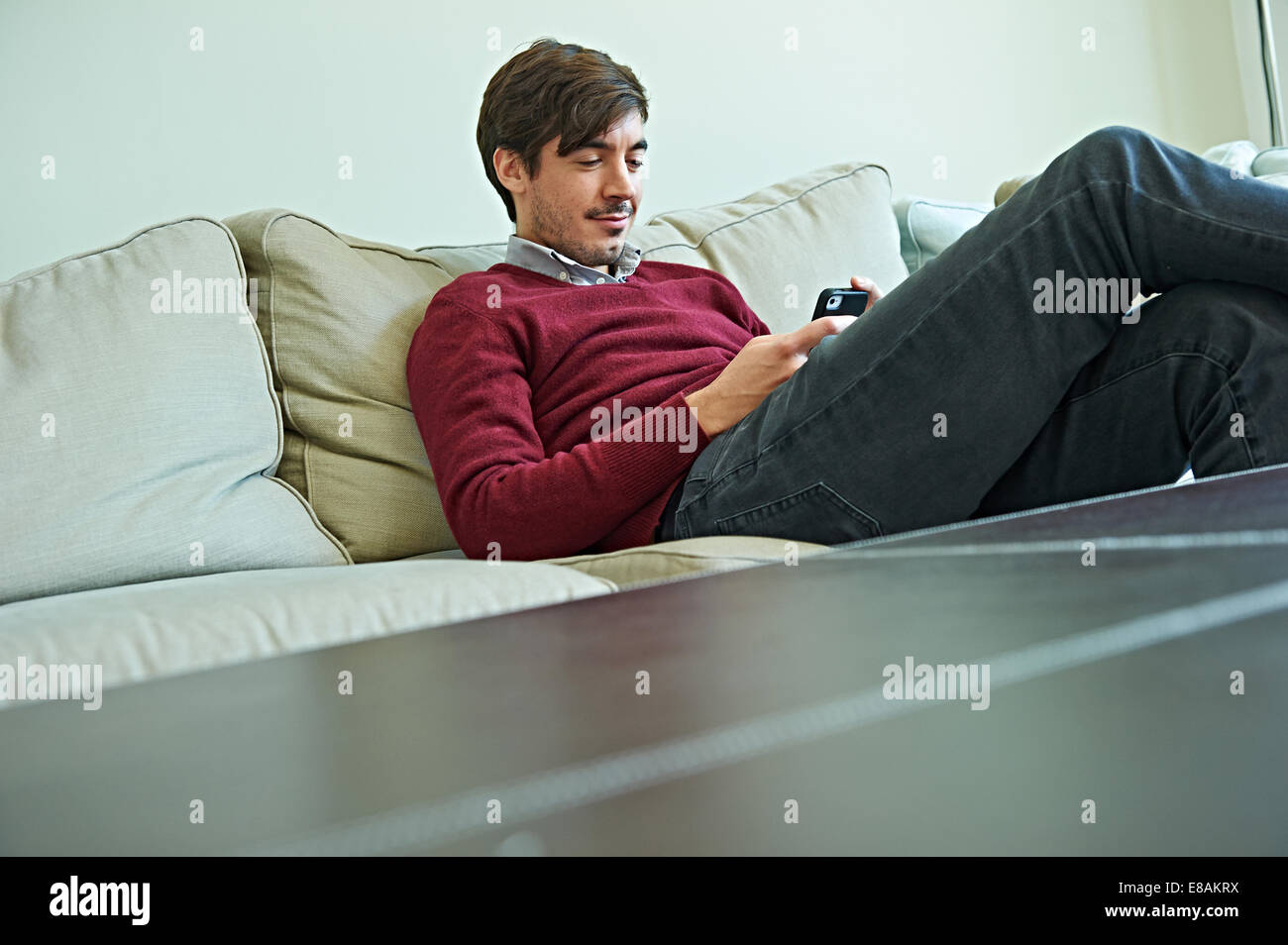 Uomo che utilizza smartphone sul divano Foto Stock